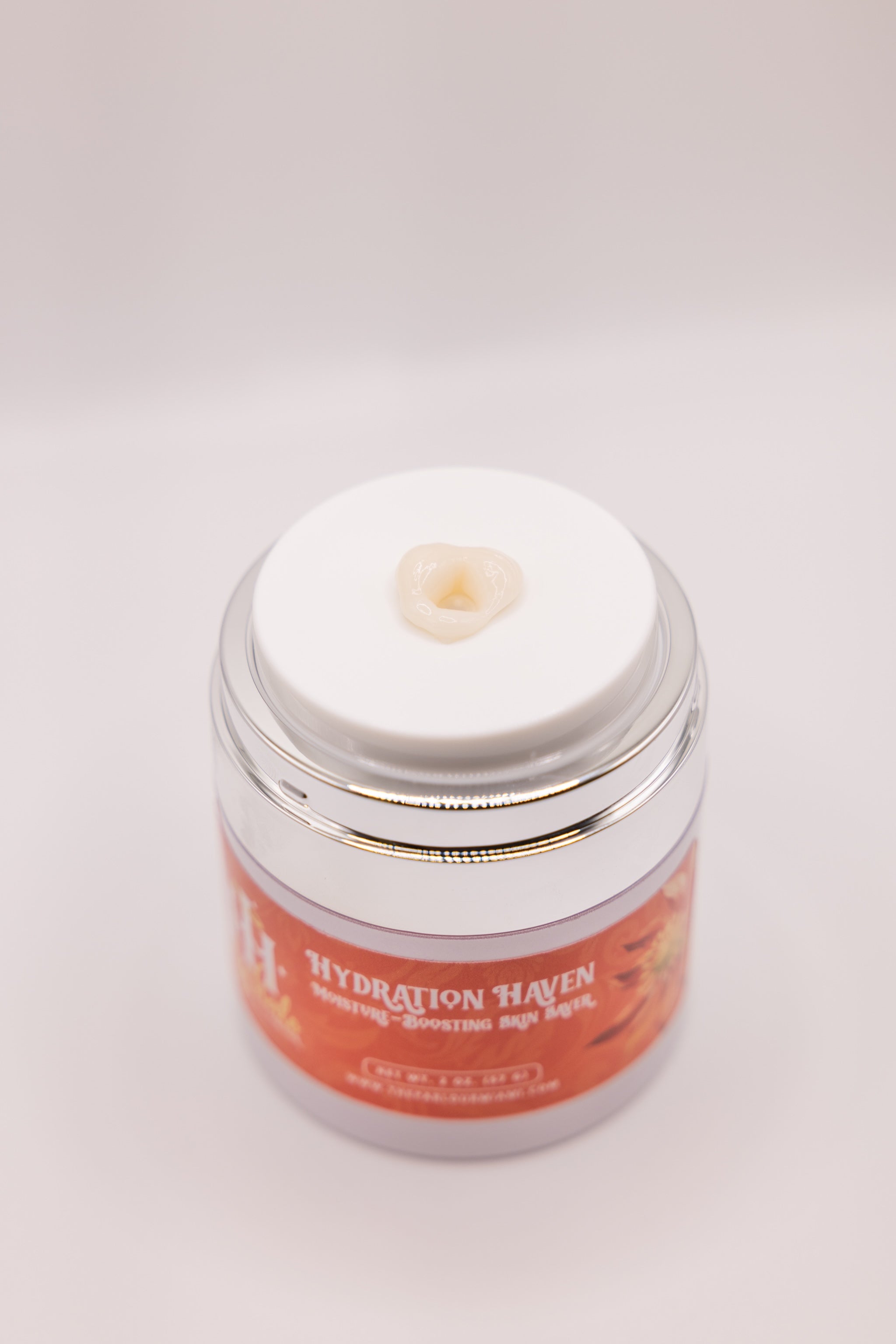 Open jar of Hydration Haven Moisture-Boosting Skin Saver by The Parlour with creamy moisturizer dispensing from the pump, showcasing rich hydrating texture for dry, dehydrated, and aging skin