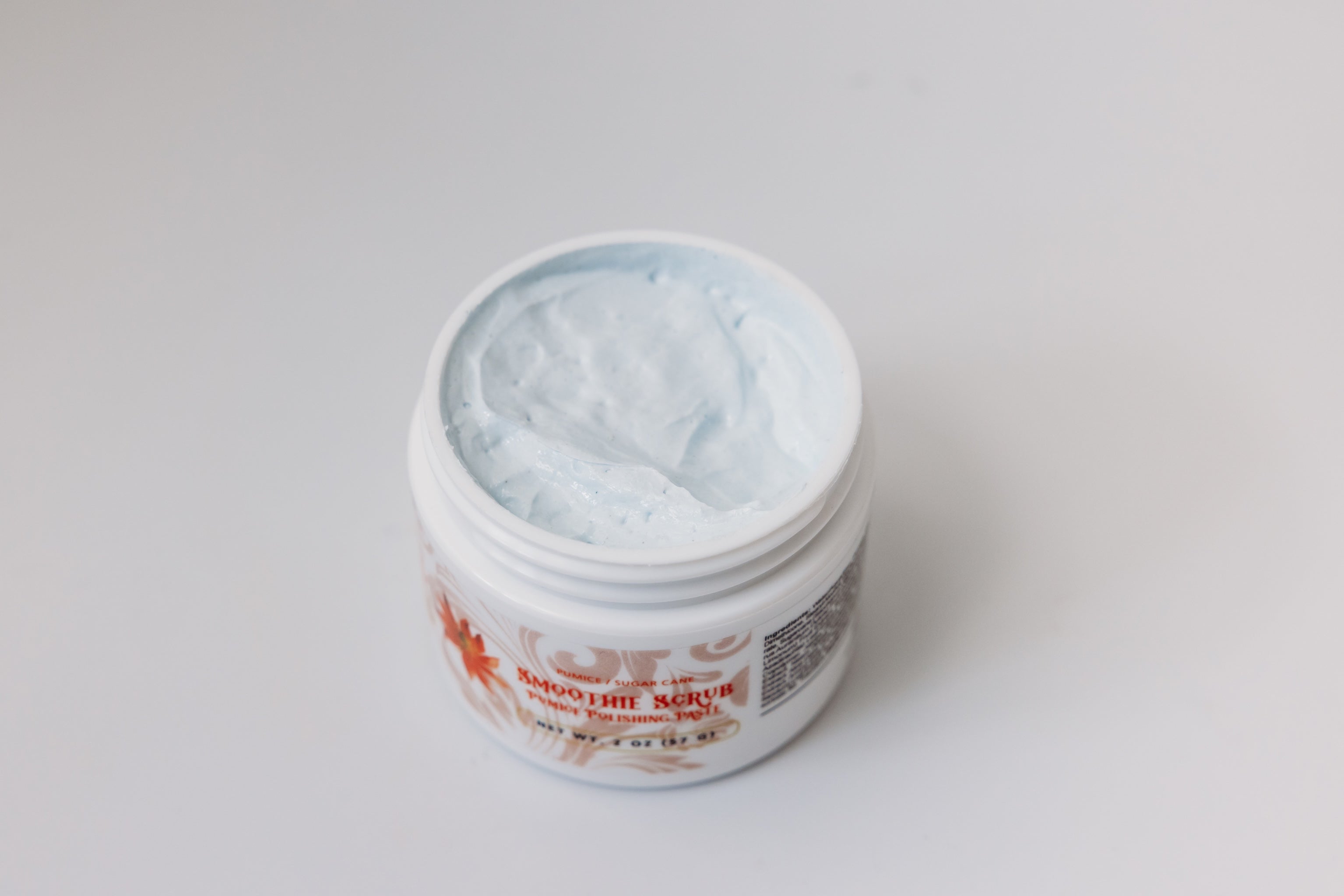 Open jar of Smoothie Scrub pumice polishing paste by The Parlour showing creamy exfoliating texture for smoothing rough skin, brightening dull complexion, and refining uneven texture.